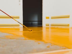 A man applying a type of epoxy flooring to a garage floor.
