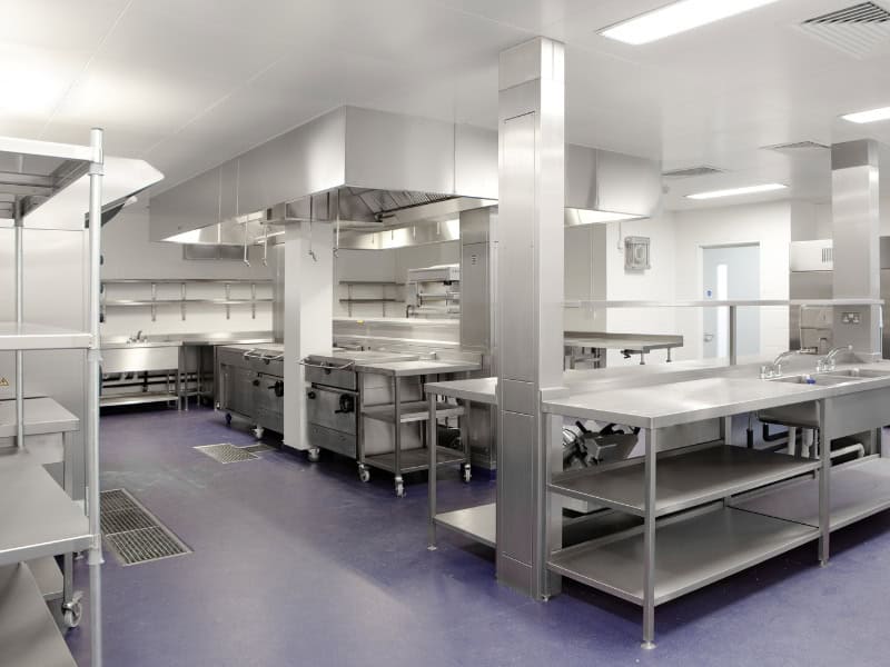A modern commercial kitchen with stainless steel equipment and epoxy flooring.